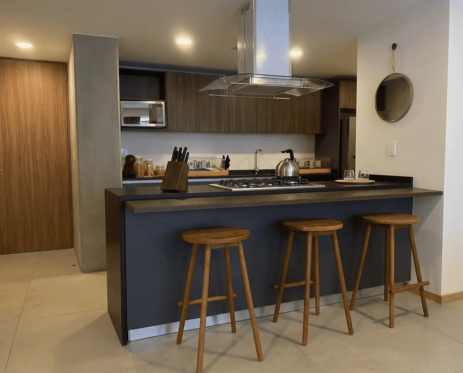 Cocina fabricada e instalada por Luis Llano: barra con cubierta oscura y carpintería en madera